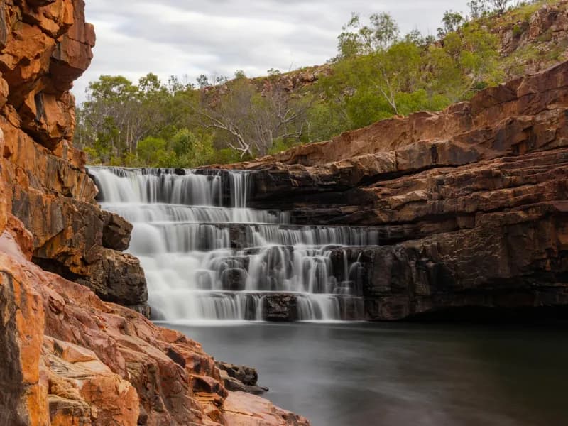 Breathtaking view of a cascading waterfall in the rugged landscape of Western Australia.