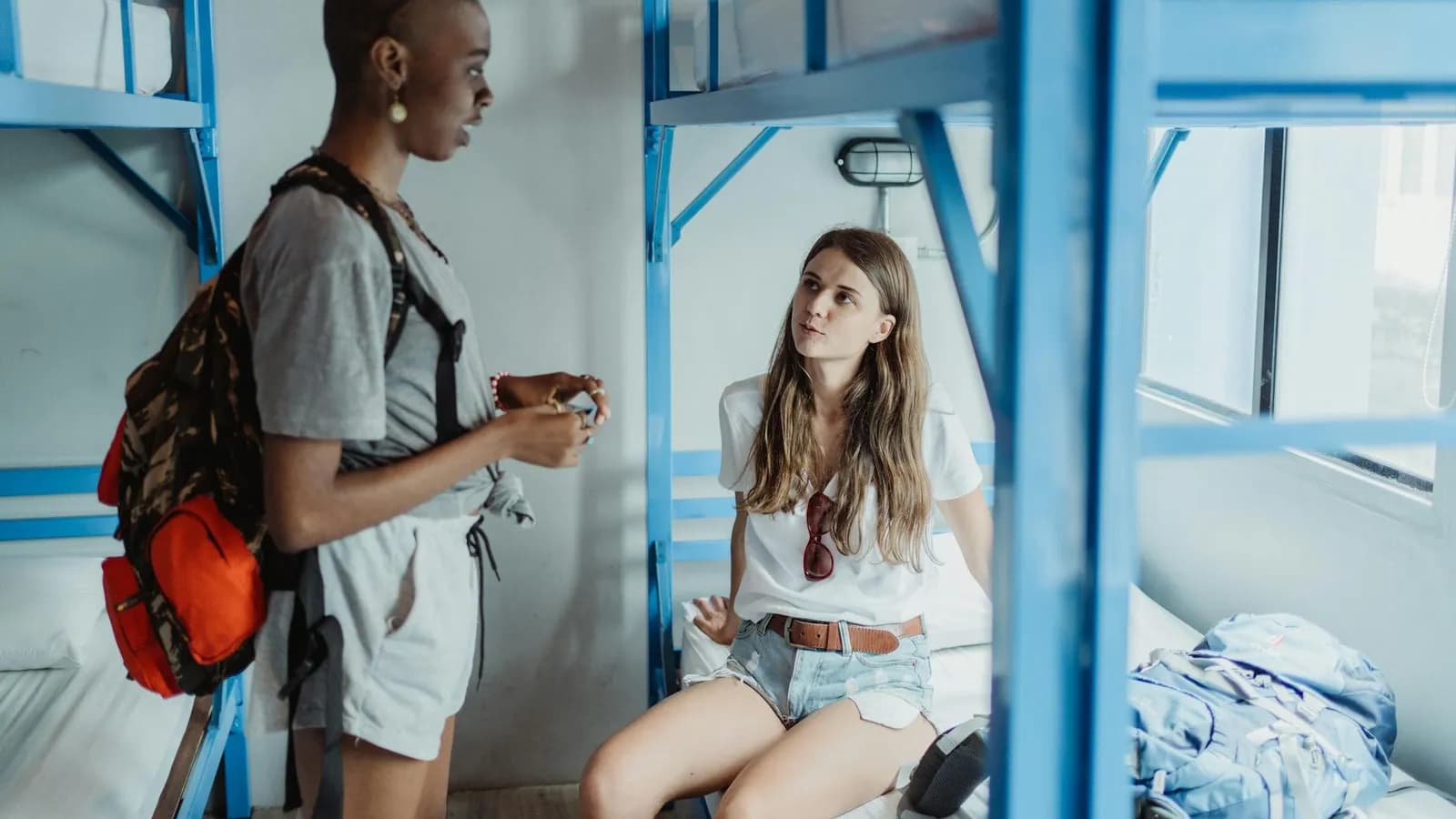 Travellers talking quietly in a hostel dormitory.