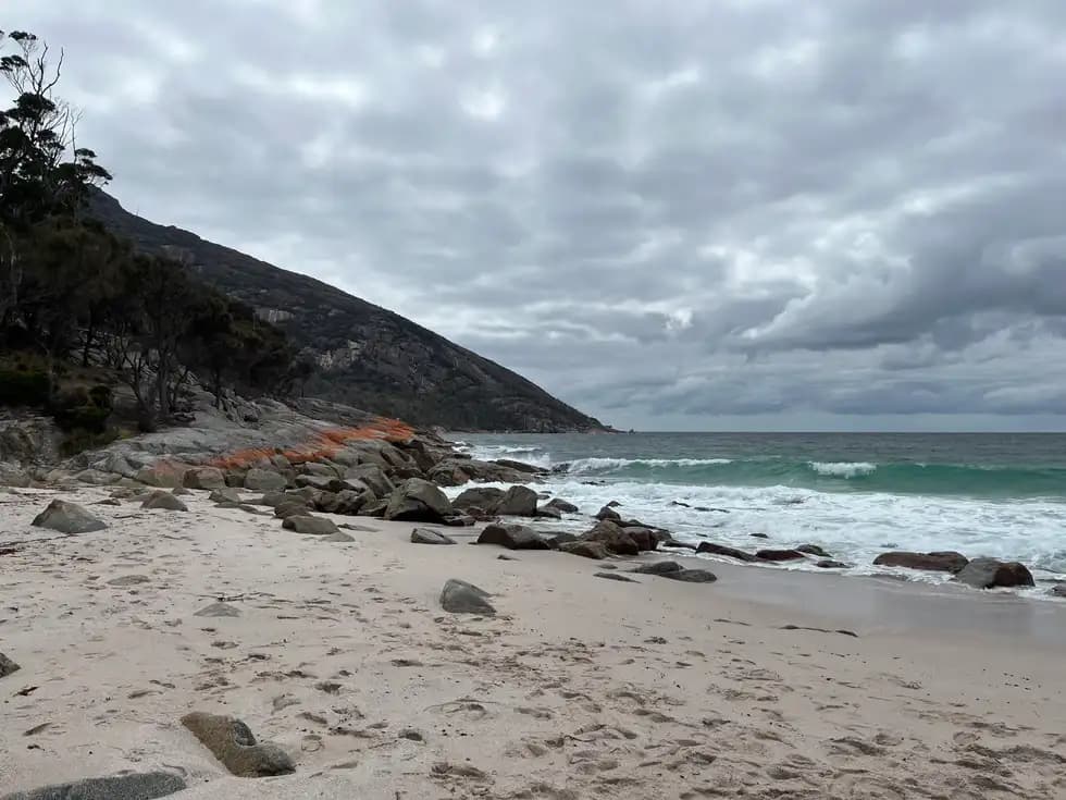 Rocky coastline with orange lichen-covered granite boulders and turquoise waves