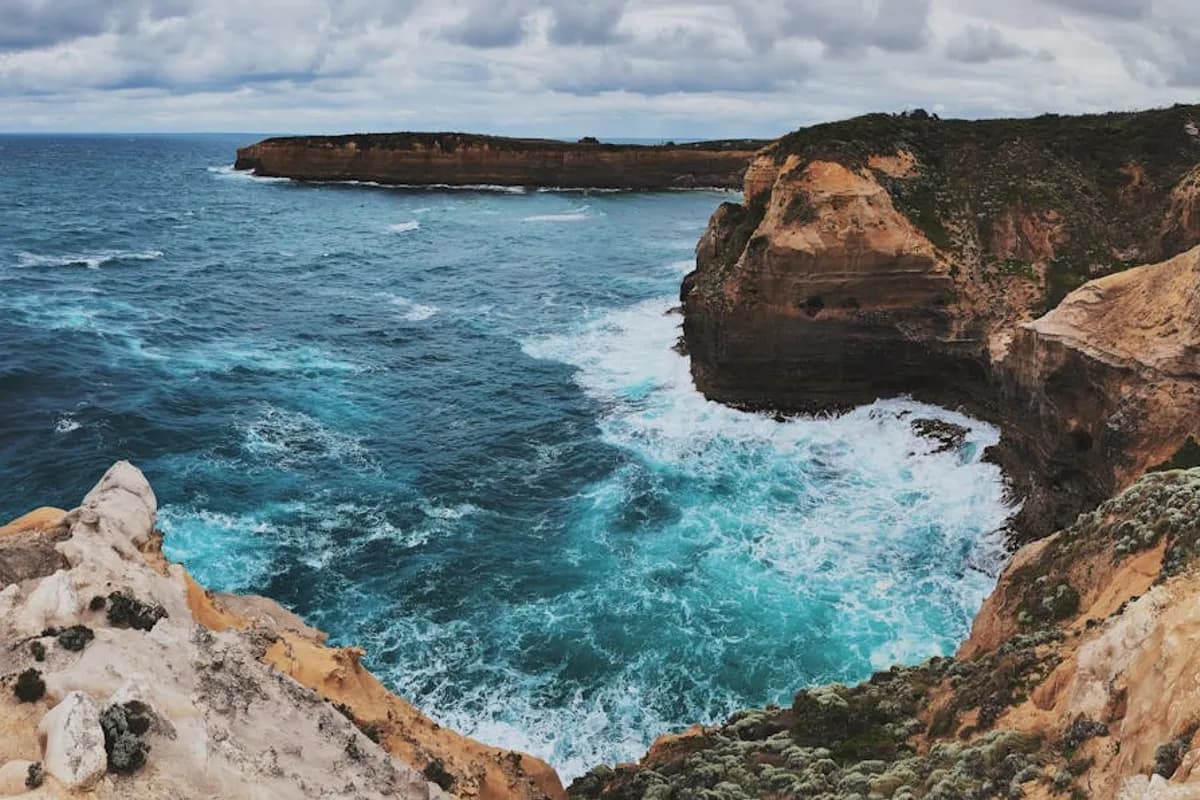 Dramatic limestone cliffs at Loch Ard Gorge with turquoise Southern Ocean waves