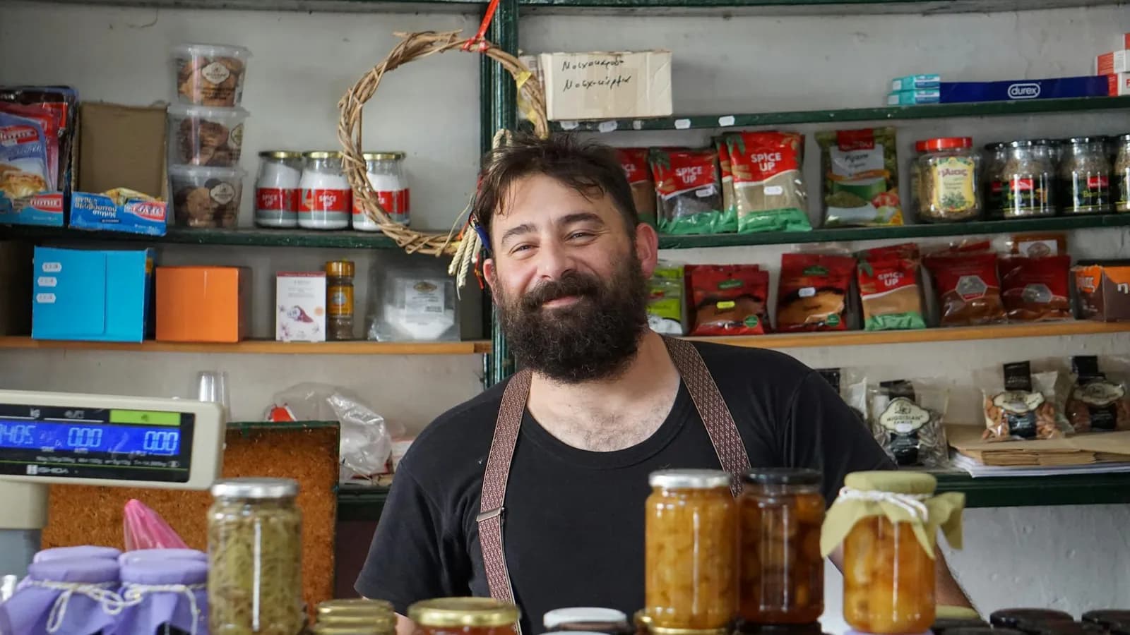 A friendly local shopkeeper greeting visitors at a market stall.