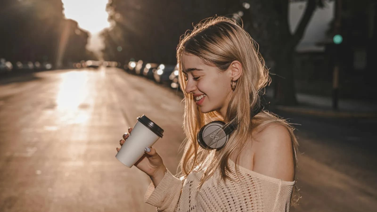 Traveller wearing headphones on a city street at sunset.