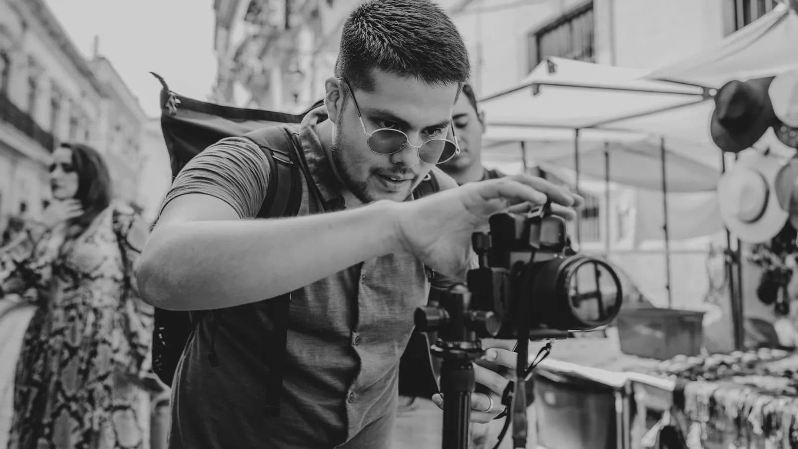 A travel photographer adjusting a camera in an outdoor market.
