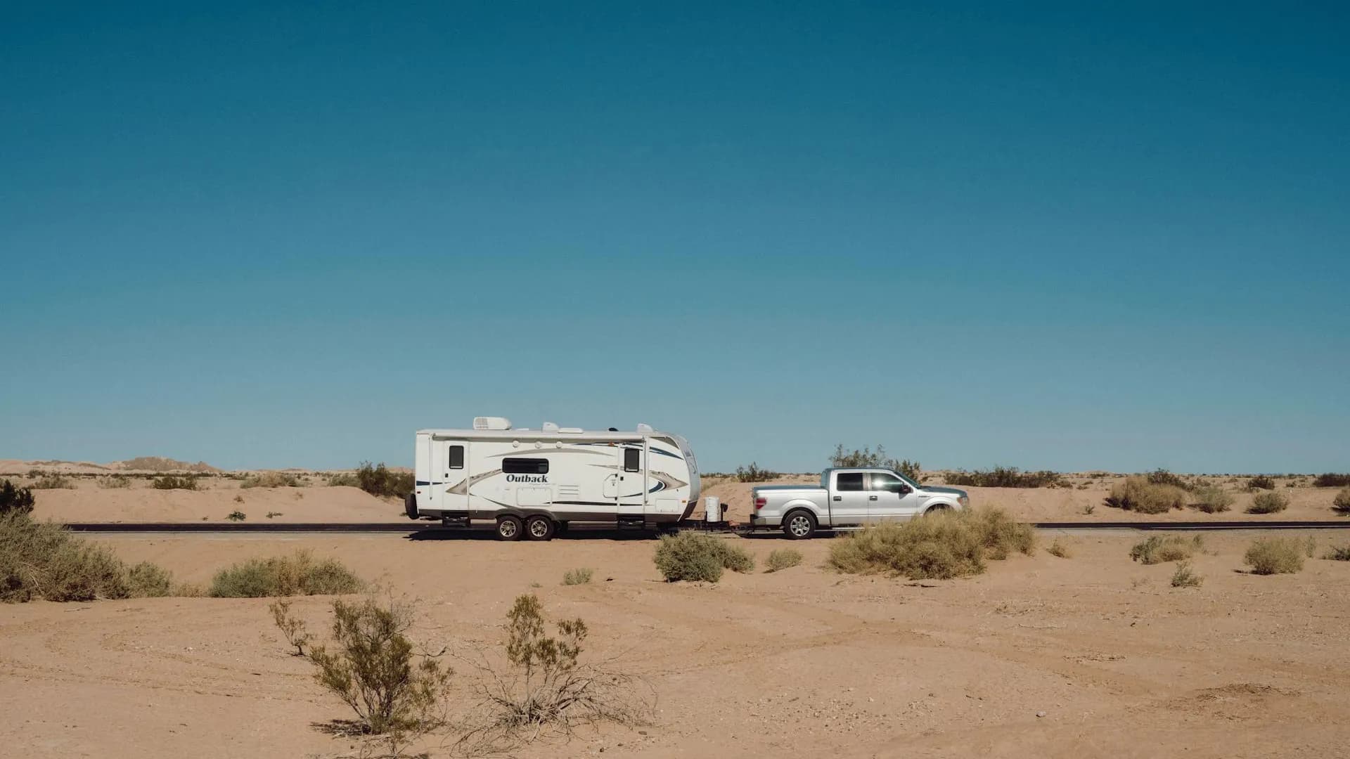 Australian road trip - caravan being towed through outback desert highway